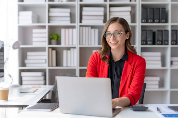 istock Charming businesswoman sitting working on laptop computer in office. 1488592369