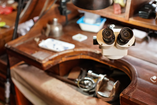 Inspection microscope at jeweller's desk, closeup detail to eyepiece lenses, blurred background