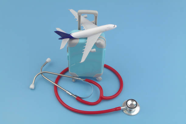 istock Airplane model on suitcase and red stethoscope on blue background. 1488596100