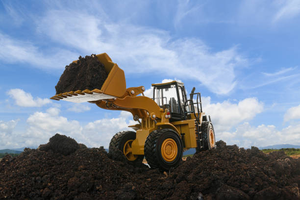 wheel loader are digging the soil in the construction site - wheel tractor scraper imagens e fotografias de stock