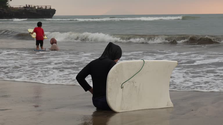 muslim woman with surfboard in the sea