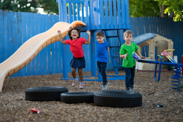 istock Three preschool children having fun playing a bean bag tossing game together on the playground of their daycare 1488597821