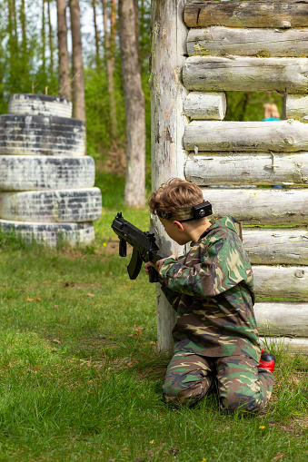 Boy weared in camouflage playing laser tag in special forest playground. Laser Tag is a command military tactical game using safe laser weapons and sensors that record hits.
