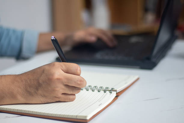 istock Male hand writing a note in a notebook concept of business people working 1488598584