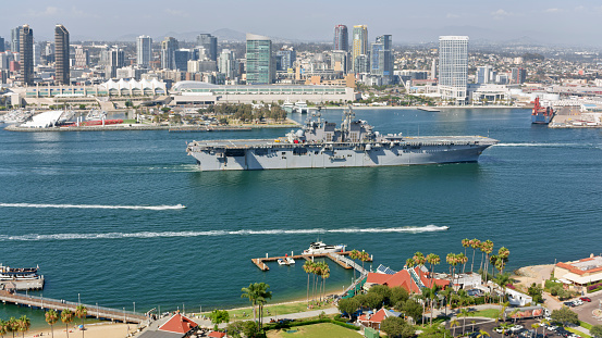 Aerial view of downtown city against military ship during sunny day, San Diego Bay, California, USA.