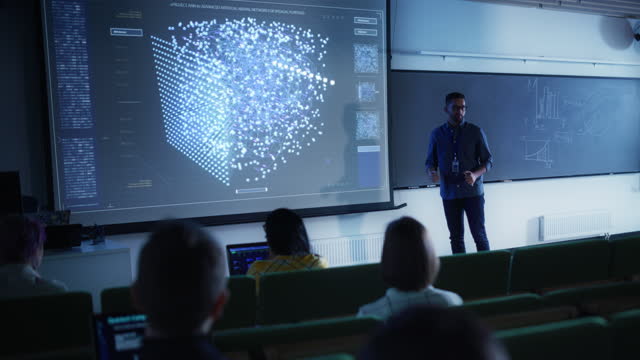 Young University Professor Explaining the Importance of Artificial Intelligence to a Group of Diverse Multiethnic Students in a Dark Auditorium. Teacher Showing Neural Network on Two Big Screens