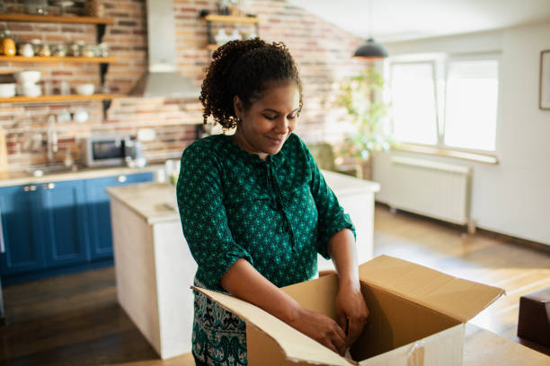istock Young woman opening up a box she received in the mail 1488604171