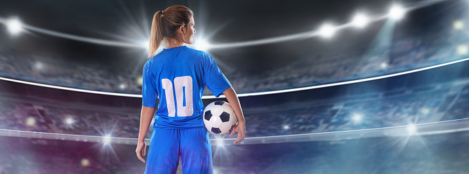 Portrait of young female soccer player standing with back with soccer ball standing on isolated Background.