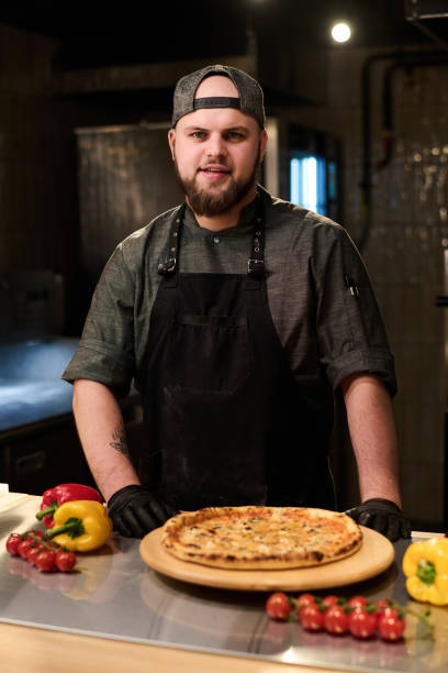 istock Young successful cook or owner of small restaurant standing by workplace 1488606035