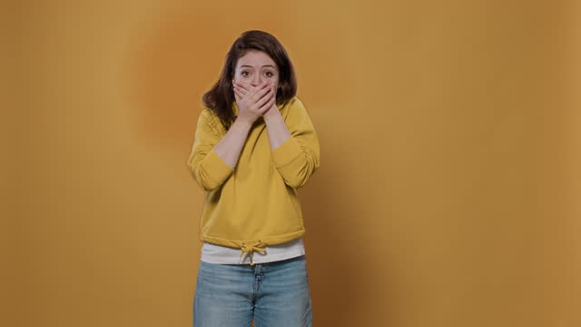 Portrait of shocked woman covering mouth with both hands surprised by unbelievable situation