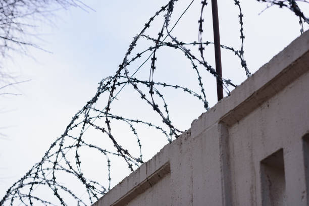istock Concrete wall with barbed wire. Coneception of prisons 1488607054
