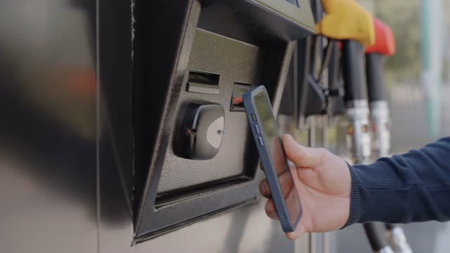 A person pays for fuel at a gas station using
