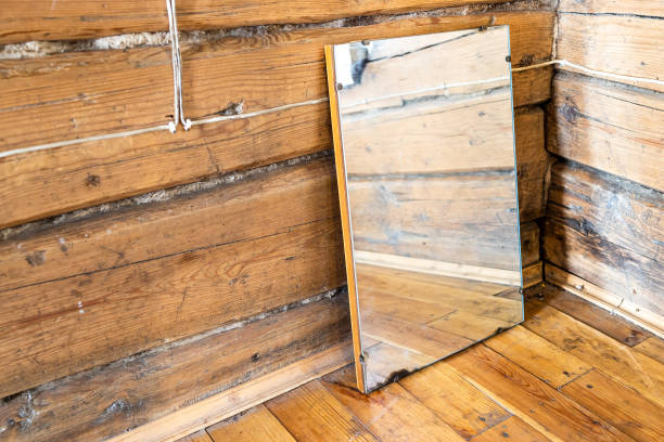 old mirror stands on wooden flooring in log house