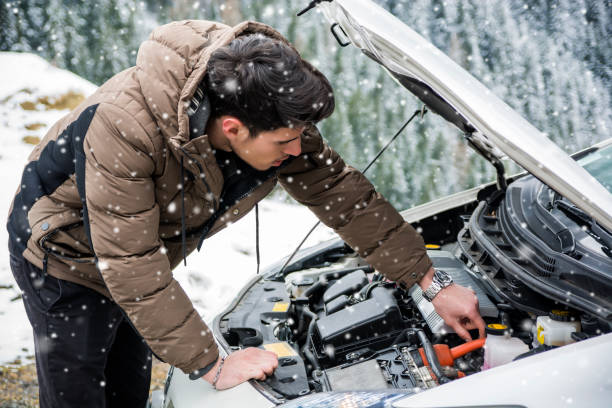 Man inspecting car engine in the snow