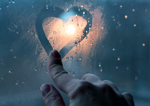 A heart on a wet window after rain is painted with a finger.