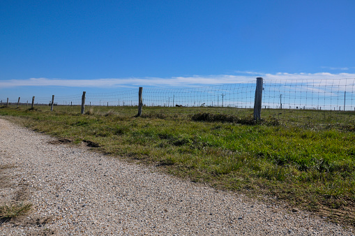 Open and empty field country road through Texas with fencing.