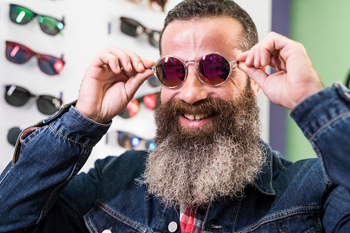 Bearded casual man selecting eyeglasses in store
