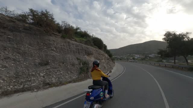 Woman riding motorcycle on road trip, fpv drone aerial view