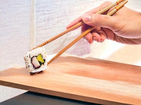 Hand with chopsticks sushi