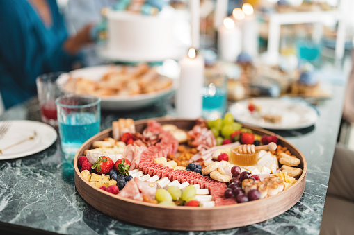 A beautiful charcuterie board at a party. Delicious foods and drinks on a blue marble table at a celebration.