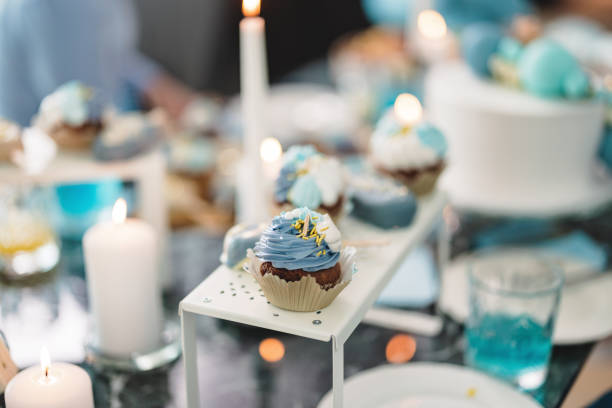 Aesthetic chocolate cupcakes with blue decoration on a tray. Delicious party desserts on the table at a baby shower.