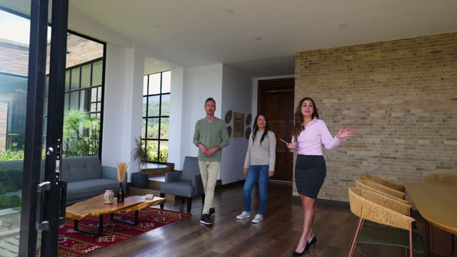Friendly female real estate agent showing a beautiful property to adult couple while holding a tablet