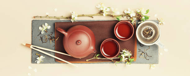 istock Asian Tea set on stone slate board, ceramic teapot, cups, dried tea and spring branches 1488617132