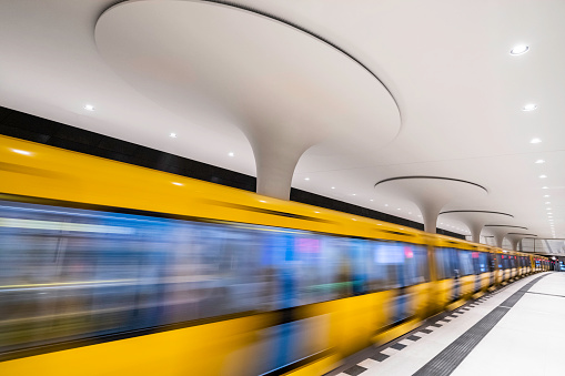 Bright yellow ubahn train zooming through undergound station in Berlin