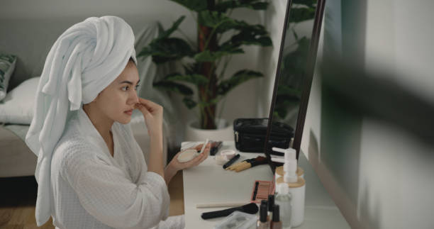 istock Young beautiful woman applying moistuizer on her face at front of mirror 1488620966