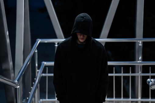 Depressed young man with a black hoodie standing alone