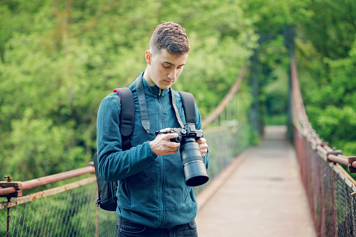 Young photographer with digital camera on a bridge in nature