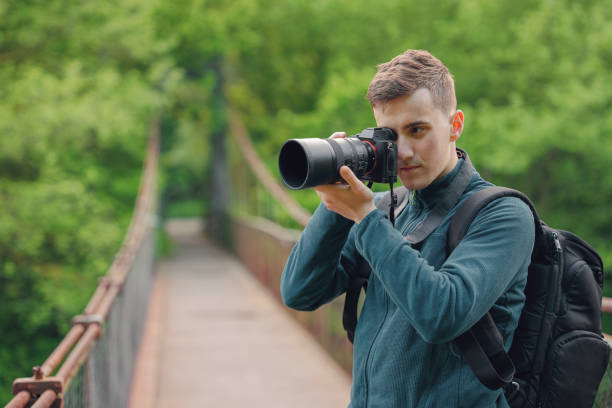 istock Young photographer with a mirrorless camera taking photos on a hanging bridge in nature 1488622575