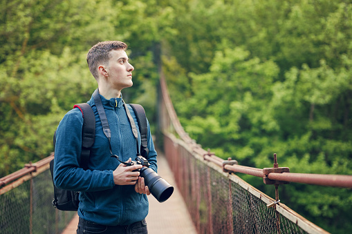 Young photographer with a digital camera on a bridge in nature