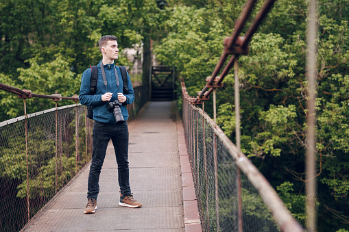 Young photographer with a digital camera on a bridge in nature