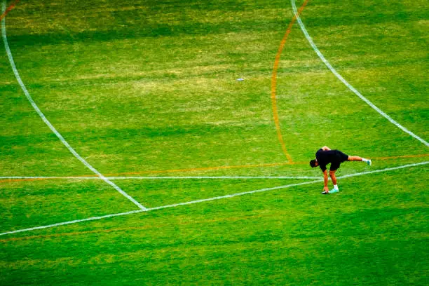 Discus throwing athlete for track and field picking up disc from green grass after throw