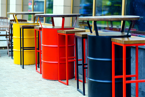 The multi-colored tables of the street cafe are made of empty barrels of petroleum products