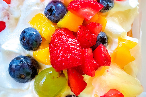 Fruity summer dessert with cream, strawberries, blueberries, grapes close-up.