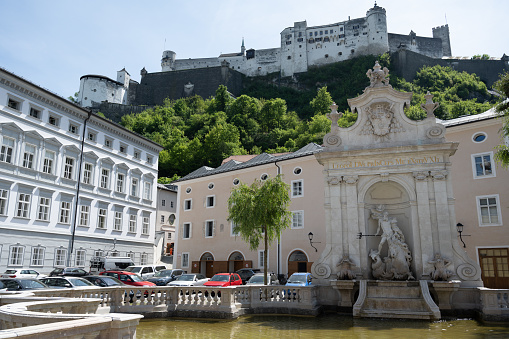 Salzburg, Austria - May 11, 2022: The Kapitelschwemme (Chapter Fountain) in Kapitelplatz (Chapter Square), and the Hohensalzburg Fortress.