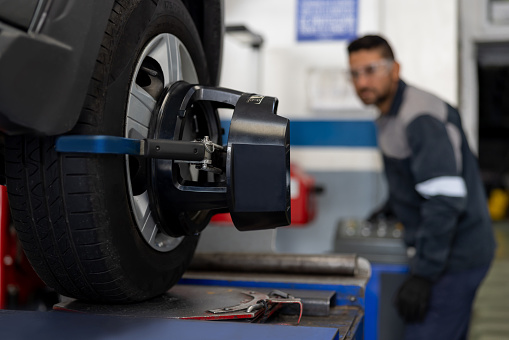 Latin American mechanic aligning a car tire while working at an Auto Repair Shop