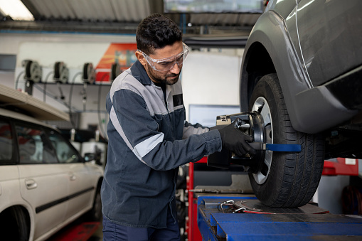 Latin American mechanic balancing a tire at a car garage - vehicle maintenance concepts