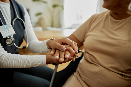 Elderly woman, caregiver and holding hands for support and empathy in a nursing home. Senior female patient with a nurse for healing, trust and kindness or communication for health and therapy