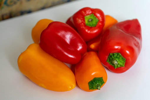 Group of small red, yellow and orange peppers, arranged on top of each other.