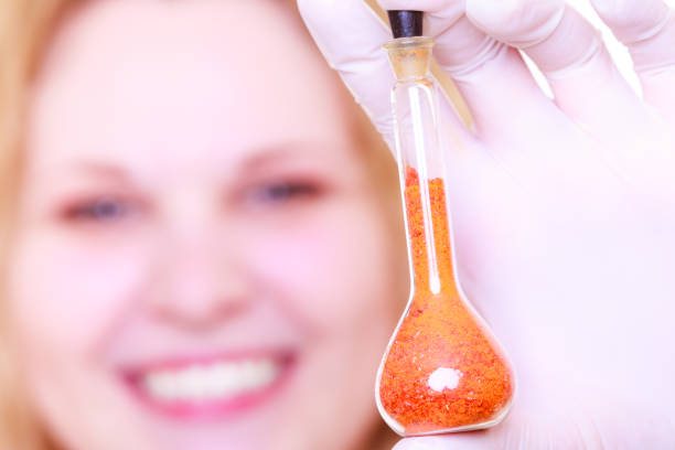 Young female scientist in the lab, examining solutions in test tubes. Woman wearing protective gloves and mask, while working in the medical or research lab. Image shot with Nikon D800 and developed from RAW file.