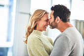Love, happiness and couple kiss in home, romance and bonding together in house with smile on face. Marriage, happy woman and mature man hug in apartment, romantic quality time and hugging in morning.