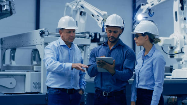 istock Engineering, automation and men and woman on tablet on machine for analysis, research and inspection. Technology, discussion and engineer team on digital tech for robotic lab, equipment and software 1488640871