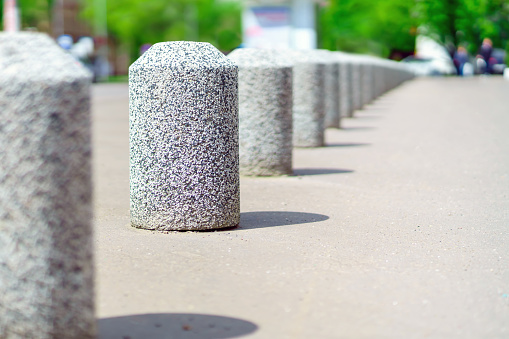 Concrete bollards with small pebbles separate the road from the pedestrian sidewalk