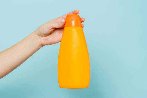 istock Woman's hand holding packaging of shampoo or conditioner on blue background. Copy space and mock up 1488642799