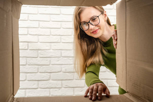istock Young woman opening a cardboard box and looking inside. Delivering parcel, unpacking. 1488642890