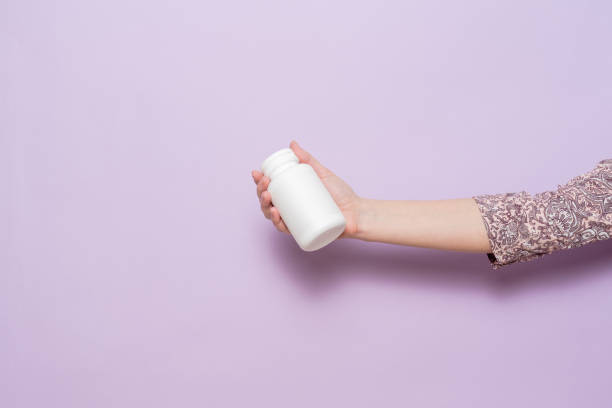 istock White plastic bottle in female hand. Packaging for pills, capsules or supplements. 1488643028