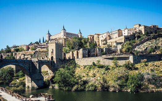 Panoramic cityscape of Toledo with Alcantara bridge over Tagus river, the city wall and the Alcazar. Castilla La Mancha, Spain